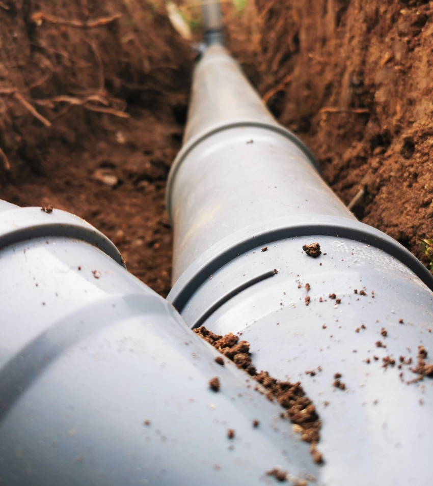Sewer line pipes in the ground, with some dirt on them.