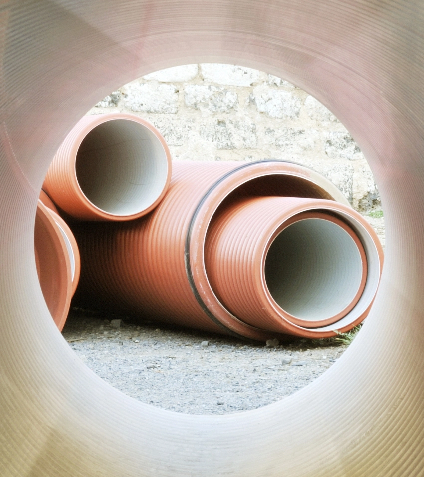 Sewer pipes lying in a stack outside.