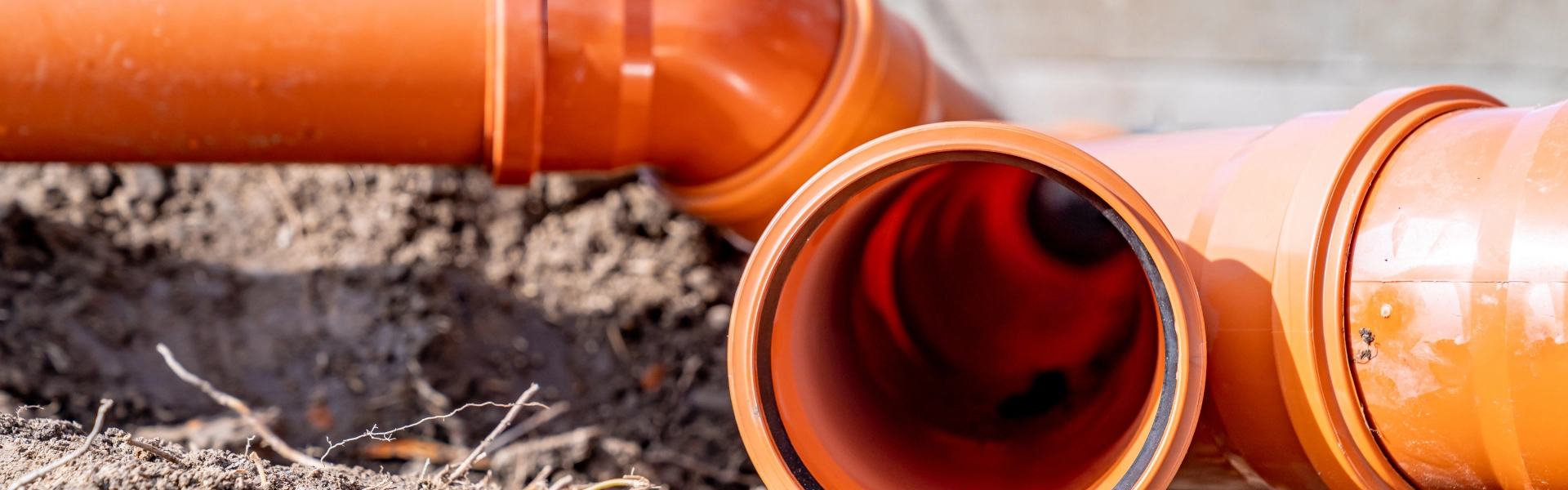 Orange sewer pipes lying on the ground.