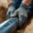 Construction worker install pipe in trench.